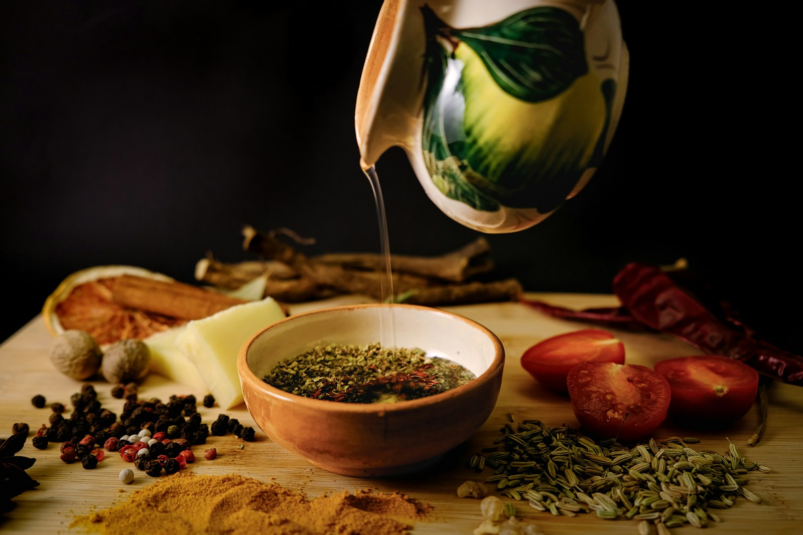 Olive oil being poured over fresh herbs.